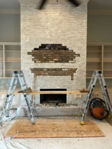 Fireplace renovation with brick wall, ladders, tools, and ceiling fan in progress – Texas Chimney LLC